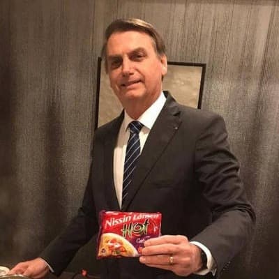 Genocida segurando um pacote de miojo